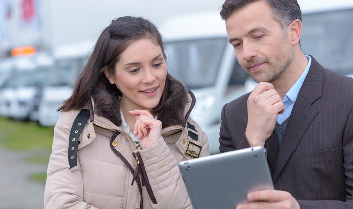 Photo of a woman talking to an RV salesman at an RV dealership.