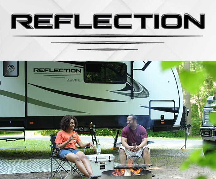 Photo of couple sitting in front of Grand Design Refection travel trailer with logo above.