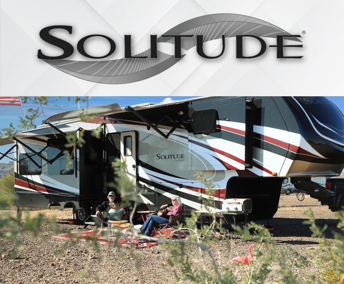 Photo of couple sitting in front of Grand Design Solitude fifth wheel with logo above.