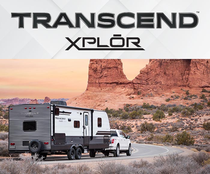 Photo of pickup pulling Grand Design Transcend XPLOR travel trailer through scenic desert area with logo above.
